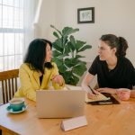 Two women, one mature and one who is younger working together at the dining table